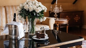 A table with a bottle, glasses, a vase of white flowers, and a cake. - Alchymist Grand Hotel and Spa (Prague)