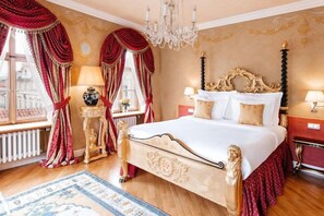 Une chambre d’hôtel classique, dotée d’un grand lit, d’une tête de lit décorée et d’un lustre.
