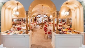 A luxurious dining area with multiple tables, ornate chandeliers, and a central archway. - Alchymist Grand Hotel and Spa (Prague)