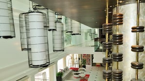 A spacious lobby with hanging metal and wooden chandeliers, a seating area with sofas and a coffee table, and a view of the interior through a glass wall. - Link Hotel (Singapore)