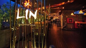 A wooden deck with a neon sign reading 'LIN' and a bar area with tables and chairs. - Link Hotel (Singapore)