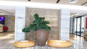 A reception area with a large potted plant, a modern reception desk, and a digital display. - Ji Hotel (Xiamen)