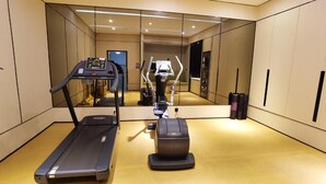 A modern gym with a treadmill, elliptical, and stationary bike. - Ji Hotel (Xiamen)