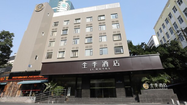 A hotel building with multiple floors, a sign indicating it's a hotel, and a staircase leading to the entrance. - Ji Hotel (Xiamen)