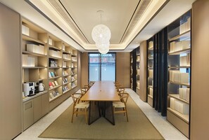 A modern library with a long table, bookshelves, and a view of a bridge. - Ji Hotel (Xiamen)