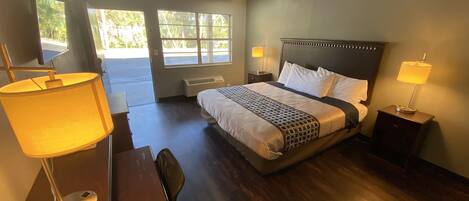 A hotel room with a large bed, two bedside lamps, a desk, and a chair.