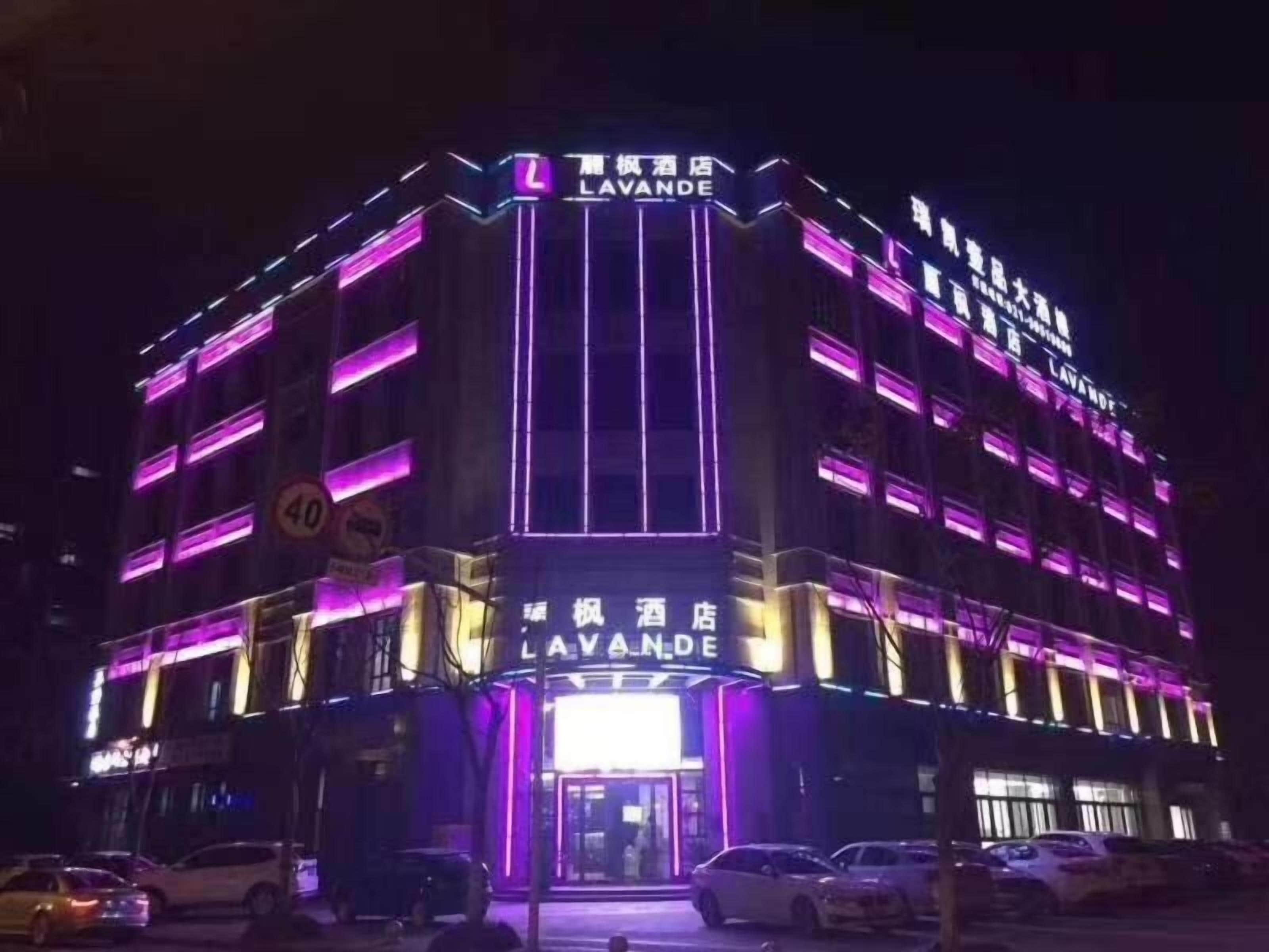 Un hôtel à plusieurs étages, doté d’une enseigne bien visible indiquant « LAVANDE » et d’une façade illuminée par des néons.
