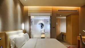 A hotel room with a large bed, a desk, and a wardrobe.
