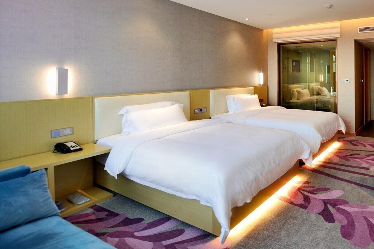 Habitación de hotel con dos camas, una mesita de noche con teléfono y piso alfombrado.