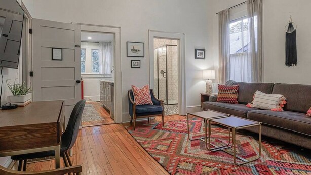 Una sala de estar moderna con una mesa de comedor de madera, un sofá y una alfombra estampada.