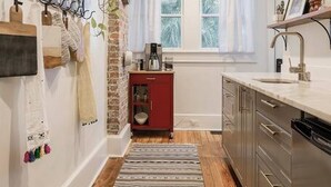 Una cocina con piso de madera, un tapete a rayas, un armario rojo y un lavavajillas de acero inoxidable.