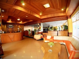 A hotel lobby with a reception desk, seating area, and a bar.