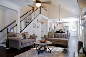 A spacious living room with a high ceiling, a staircase, and a kitchen in the background. - The Garnet Door Bungalow - 4 Bed, 3 Bath, DT Cola (Columbia)
