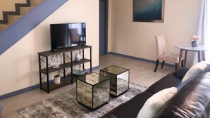 A living room with a staircase, a television on a stand, a glass coffee table, a sofa, and a painting on the wall. - Dreamy Singer Island Beach Retreat (Singer Island)