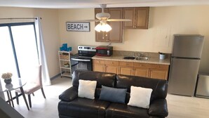 A modern kitchen with a black leather sofa, wooden cabinets, and a refrigerator. - Dreamy Singer Island Beach Retreat (Singer Island)