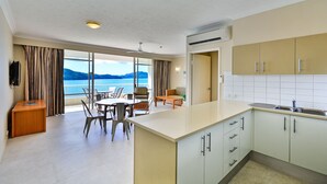 Une cuisine moderne dotée d’un grand îlot central, d’un coin repas avec des chaises et offrant une vue sur la mer.