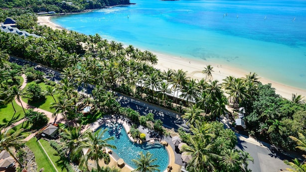 Un complexe hôtelier doté d’une plage, d’une piscine et d’une végétation luxuriante.