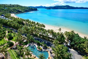Un complexe hôtelier doté d’une plage, d’une piscine et d’une végétation luxuriante.