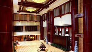 En rymlig entréhall med ett klinkergolv, ett stort, runt bord i mitten som är dekorerat med blommor och traditionell träpanel på väggarna.
