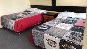 Two single beds with checkered bedding, a nightstand, a lamp, and framed pictures on the wall. - The Scoot Inn (Port Orange)