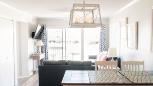 A dining area with a wooden table, two chairs, and a hanging light fixture. - Cozy Condo for your family, indoor pool&Putt Putt. (Atlantic Beach)