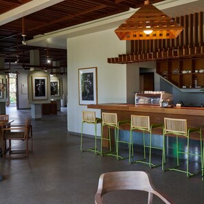 A modern bar area with wooden stools and a bar counter, surrounded by framed artwork on the walls.