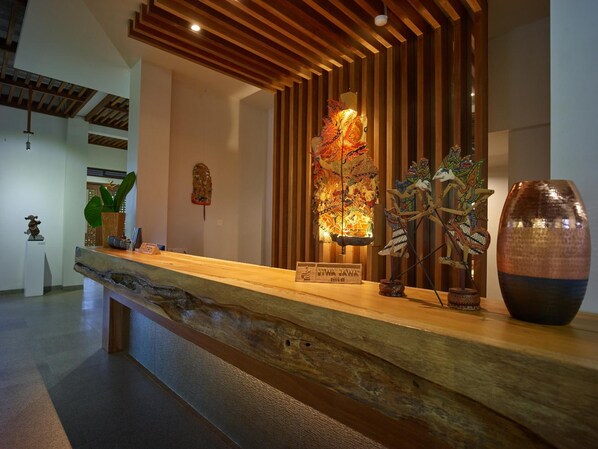 Una reception con scrivania in legno, un elemento decorativo a parete e un vaso grande.