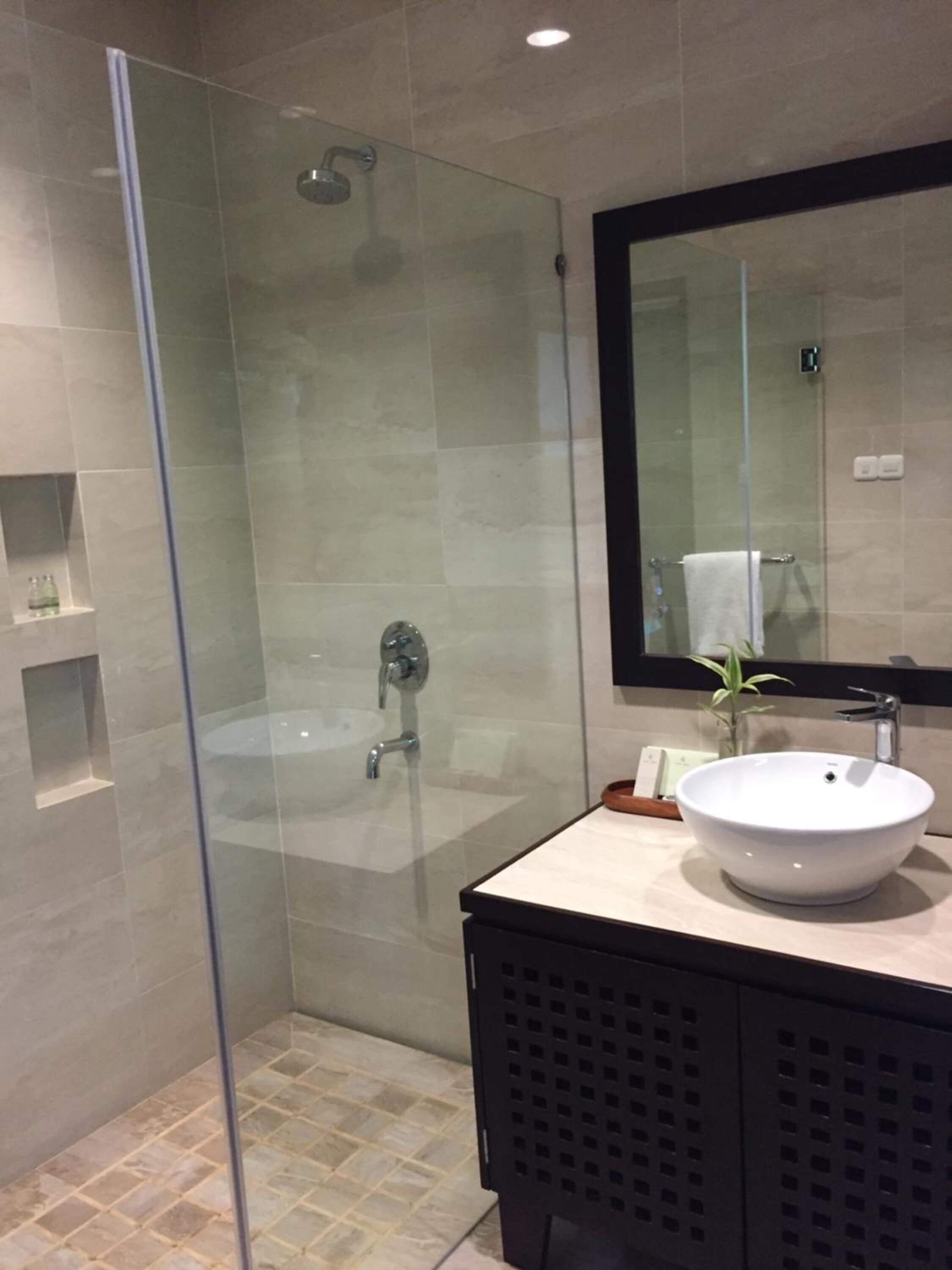 Une salle de bain moderne avec une douche à parois de verre, un lavabo blanc et un grand miroir.