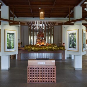 Eine Kunstgalerie mit einer zentralen Skulptur, gerahmten Kunstwerken an den Wänden und einer Holzkiste im Vordergrund.