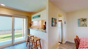 A kitchen with a sliding glass door to the outdoors, a bar stool, a refrigerator, and a dining table with chairs.