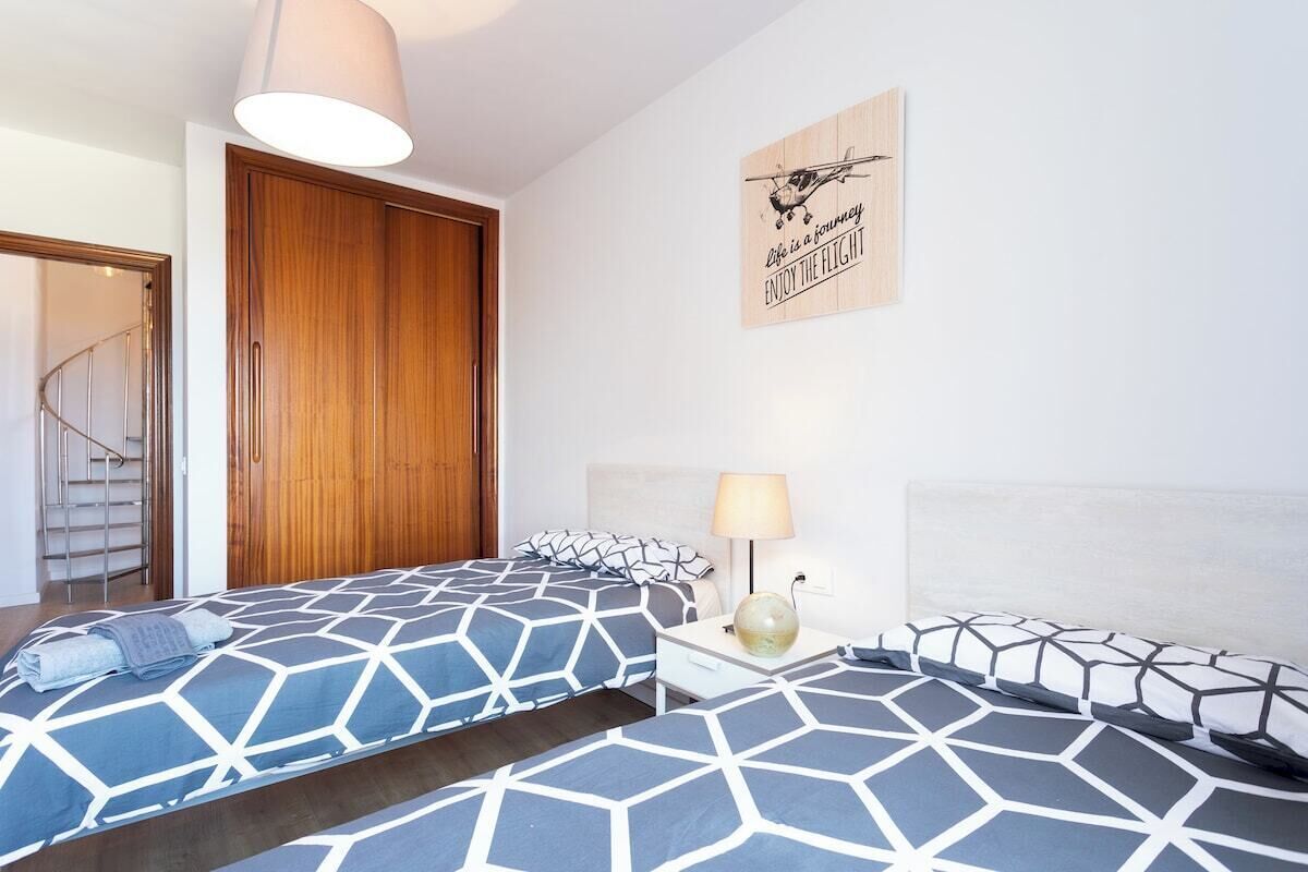 Un dormitorio con dos camas, un armario de madera, una escalera de caracol y un cartel en la pared.