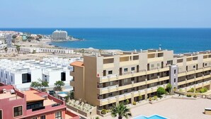 A coastal hotel with multiple balconies, a swimming pool, and a view of the sea.