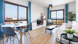 A modern living room with a dining area, large windows with a city view, and a cozy seating arrangement.