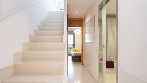 A modern interior with a staircase leading to a bedroom with a bed and a window.