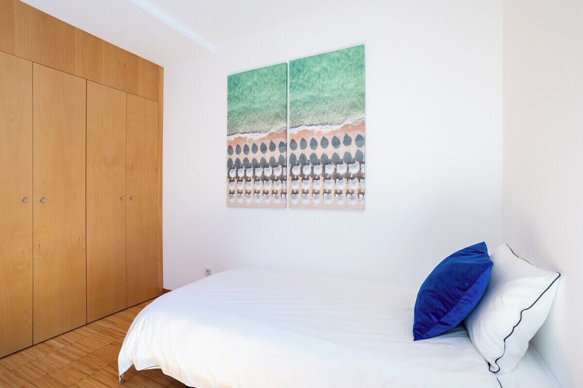 Un dormitorio con una cama, un armario de madera y una obra de arte en la pared.