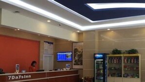 A 7DaysInn reception area with a reception desk, a digital display, vending machines, and a cabinet with amenities. - 7 Days Inn (Dongying)