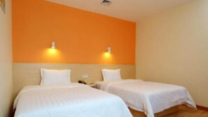 A hotel room with two single beds, a wooden floor, and an orange accent wall. - 7 Days Inn (Dongying)