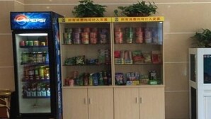 A vending machine with a Pepsi logo, a shelf stocked with various snacks, and a cabinet with multiple compartments. - 7 Days Inn (Dongying)