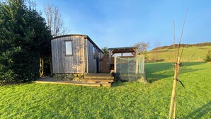 A rustic wooden cabin with a small porch and a fenced area.
