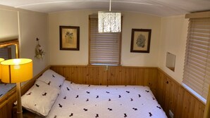 A bedroom with a bed, a nightstand, a lamp, and two framed pictures on the wall.