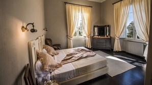 A bedroom with a bed, a dresser, a mirror, and two windows with curtains. - Villa del Poeta - Homelike Villas (Loro Ciuffenna)
