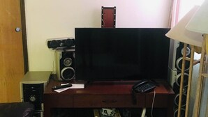 A living room with a television on a wooden stand, a speaker, and a lamp. - Come, Relax and feel at Home (Tijuana)