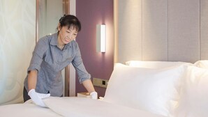 A hotel room with a neatly made bed, a wall-mounted light, and a door with a mirror. - Lavande Hotel Chongqing Jinkai Avenue Aegean Sea Shopping Park (Chongqing)