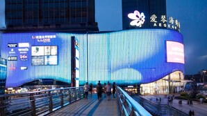 A modern building with vertical blue panels and a large flower logo. - Lavande Hotel Chongqing Jinkai Avenue Aegean Sea Shopping Park (Chongqing)