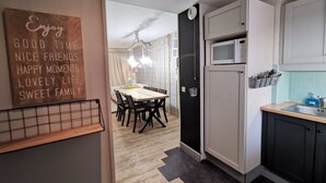 Cozinha moderna com micro-ondas, pia e suporte para utensílios. Uma área de jantar com mesa e cadeiras pode ser vista ao fundo.