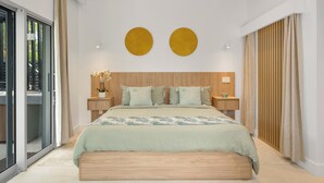 Un dormitorio moderno con una cama grande, cabecera de madera, dos adornos circulares en la pared y un ventanal corredero a un espacio exterior.