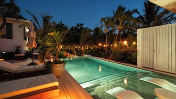 A swimming pool with lounge chairs and a potted plant.