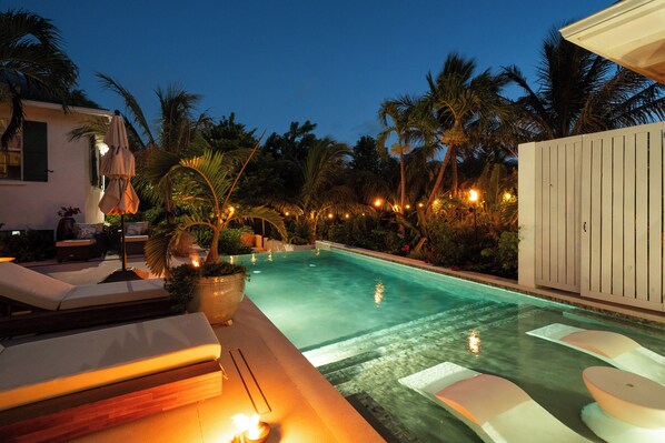 A swimming pool with lounge chairs and a potted plant.