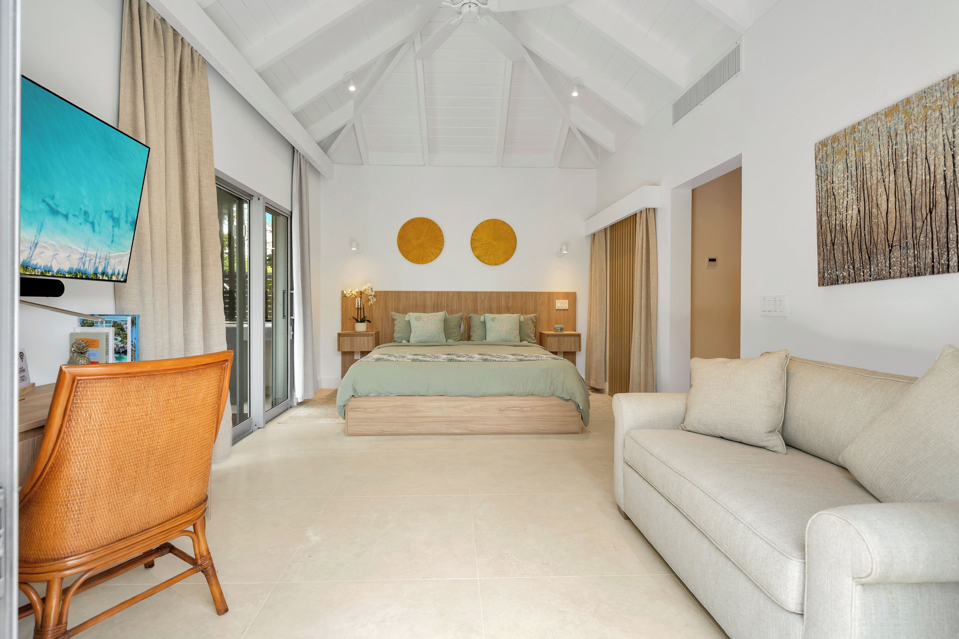 A modern bedroom with a bed, a sofa, a chair, and a TV.