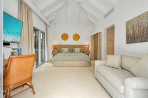 A modern bedroom with a bed, a sofa, a chair, and a TV.